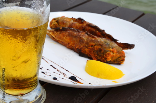 beer in a glass goblet on the background of fried fish with lemon