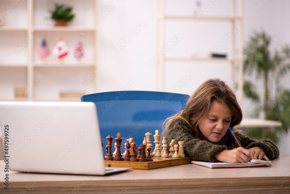 Young little girl playing chess at home