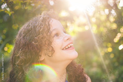 Portrait of beautiful curly hair girl smiling. Sunlight with flare.