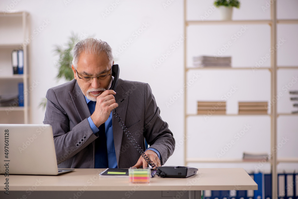 Old male employee working at workplace Old male employee working at workplace
