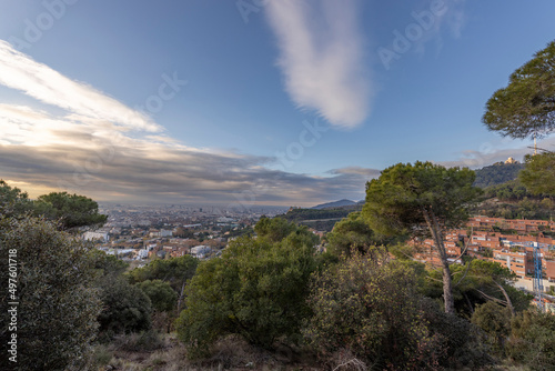 Picturesque landscape of Barcelona from the hill in the early morning. Pine trees in the foreground. Sunbeams through the clouds. View of Mount Tibidabo. Autumn in Barcelona  Spain.