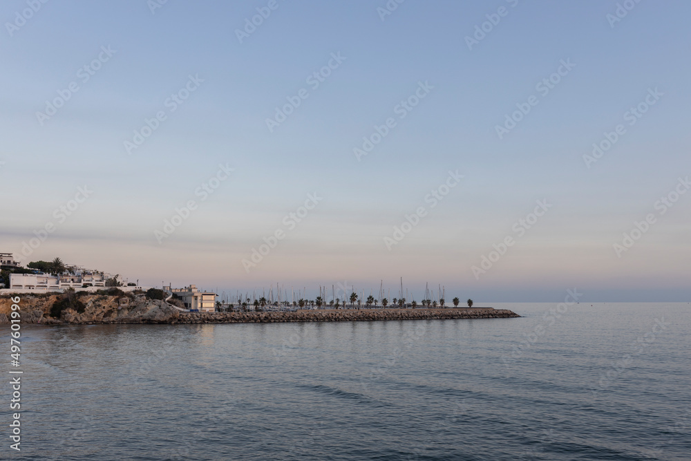 Picturesque sea evening landscape. Sunset over the mediterranean sea. Evening city, sea and sunset. The sun is above the horizon line.