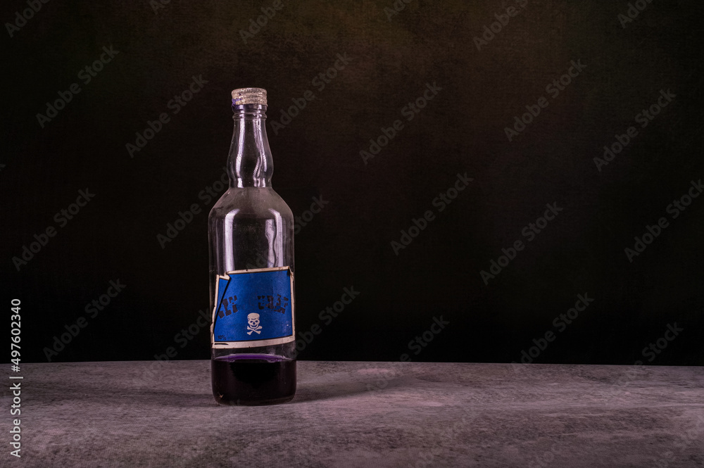denaturat zatruty alkohol w starej butelce na ciemnym tle - obrazy, fototapety, plakaty 