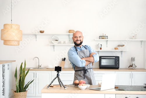 Male chef with tasty peach muffins in kitchen