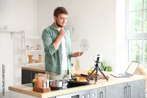 Thoughtful young man with tablet computer watching cooking video tutorial in kitchen