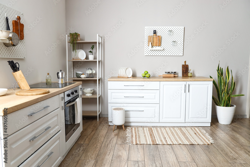 Interior of modern kitchen with shelving unit, pegboard and modern furniture