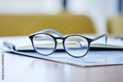 Being a visionary is ones greatest strength. Shot of glasses and paperwork lying on a desk in an empty office during the day.