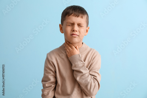 Ill little boy with sore throat on color background