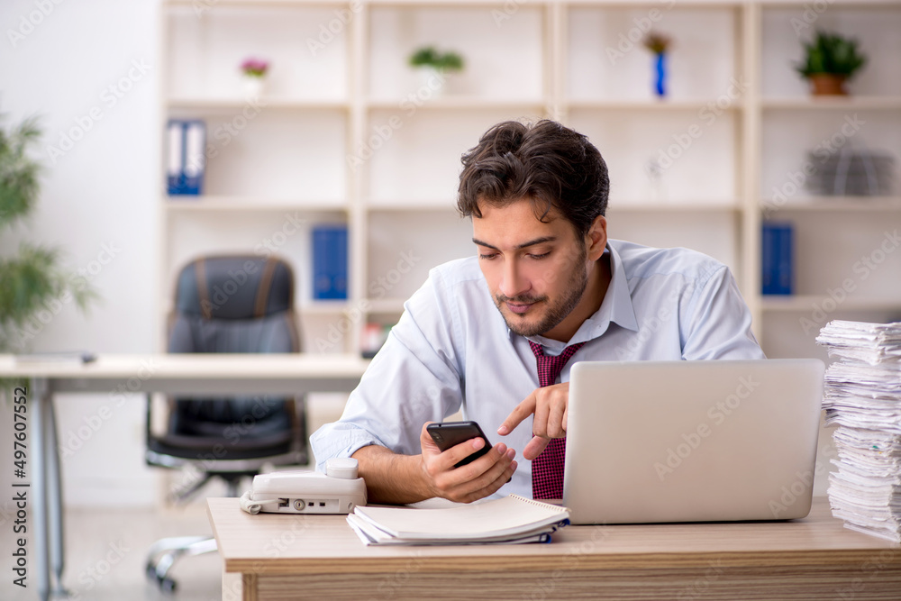 Young male employee and too much work in the office Young male employee and too much work in the office