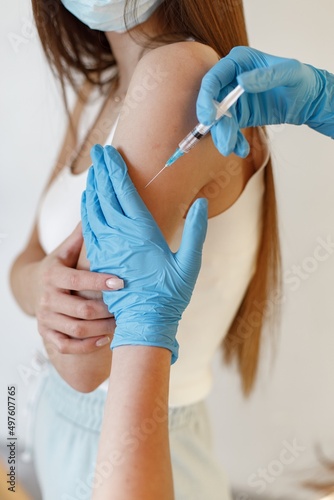 Woman in mask receiving an injection in her arm