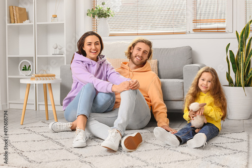 Young family sitting on soft carpet at home