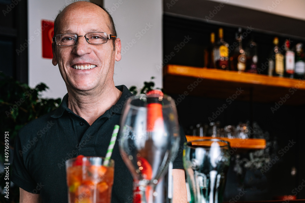 portrait of a mature waiter carrying a tray of beverages
