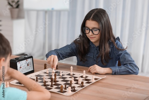 Little children playing chess during tournament in club