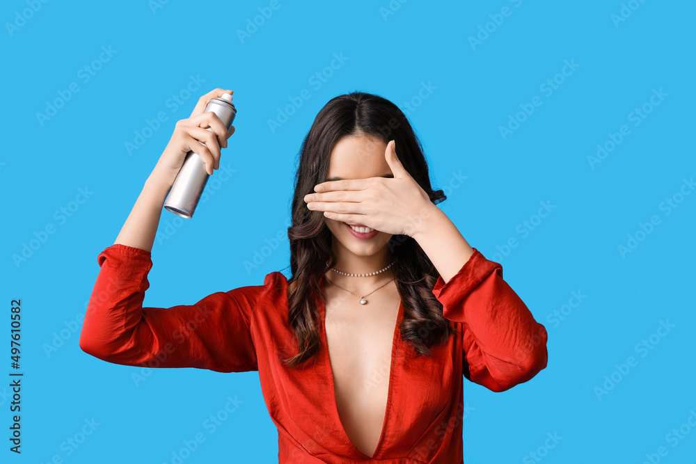 Beautiful young woman with hair spray on blue background Beautiful young woman with hair spray on blue background