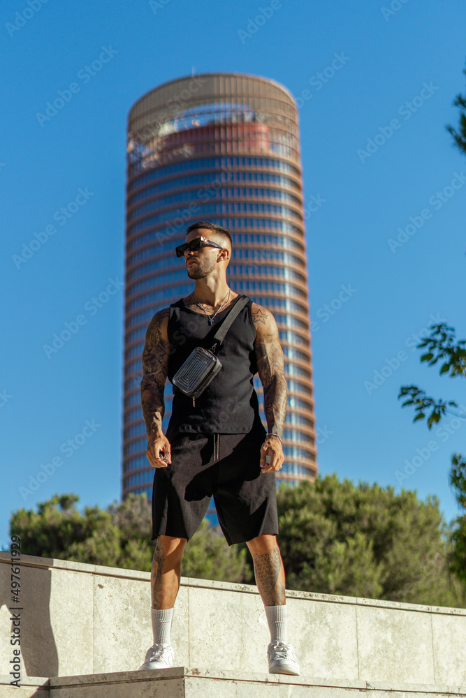 Caucasian sporty male with tattoos on a background of a high-rise building