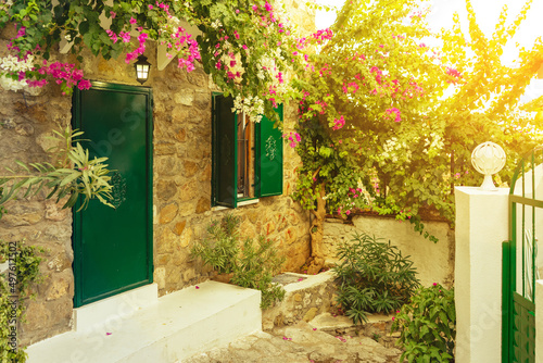 Beautiful courtyard of an old brick house in old town with blooming pink flowers of bougainvillea. Golden hour, rays of the sun at sunset. Travel, vacation concept. European architecture