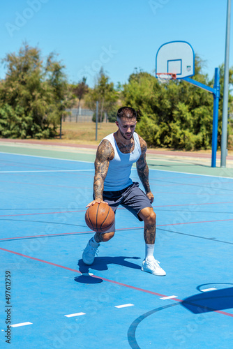 Sporty Caucasian male with tattoos playing basketball © Fran Martínez