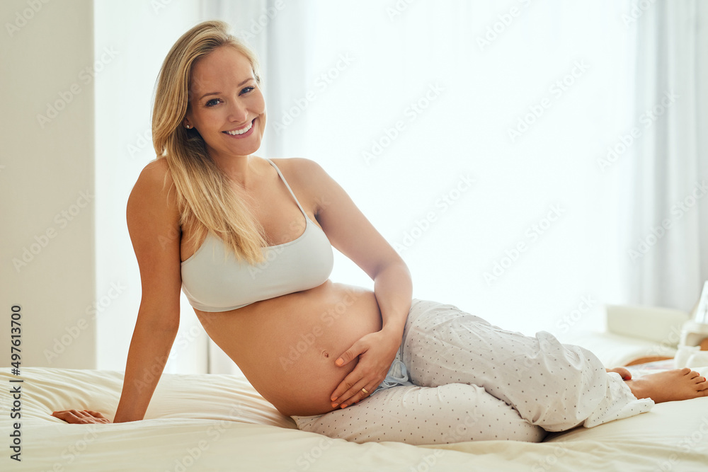 Happy mamas make happy babies. Shot of a pregnant woman touching her belly while sitting on her bed. Happy mamas make happy babies. Shot of a pregnant woman touching her belly while sitting on her bed.