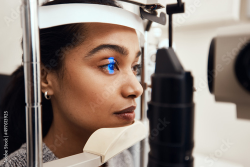 Keep as still as possible. Shot of a young woman getting her eyes examined with a slit lamp.