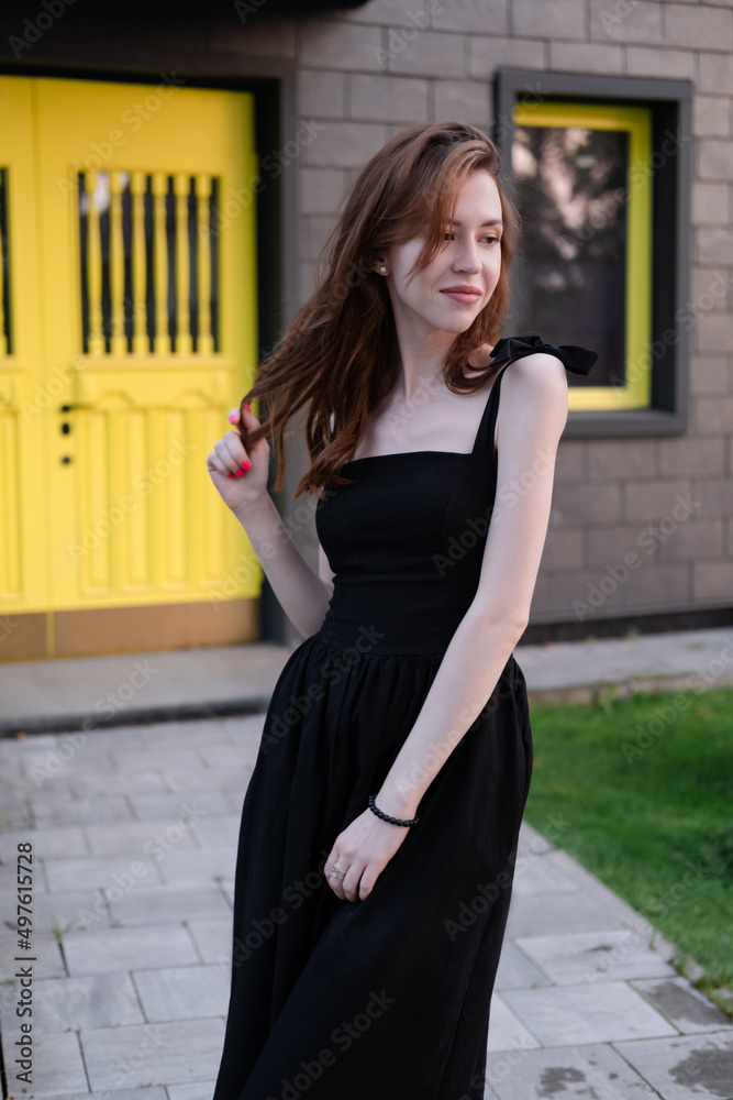 happy young woman in a black dress in front of modern building with yellow door. housewarming. buying a house. happy life in private house. new home happy young woman in a black dress in front of modern building with yellow door. housewarming. buying a house. happy life in private house. new home