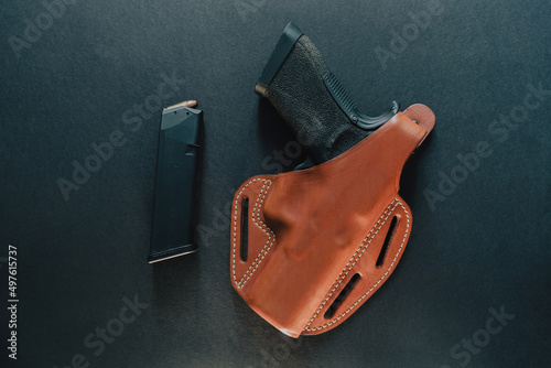 Isolated shot of a gun covered with leather holster on the table photo