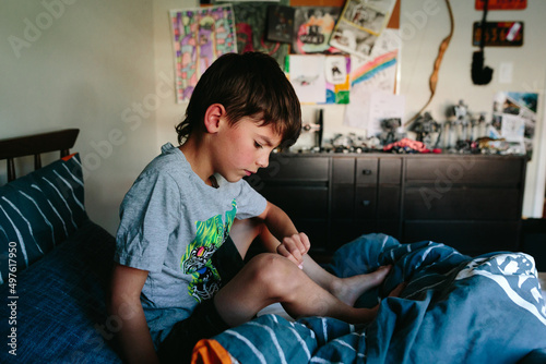 boy sits quietly on bed in his room photo