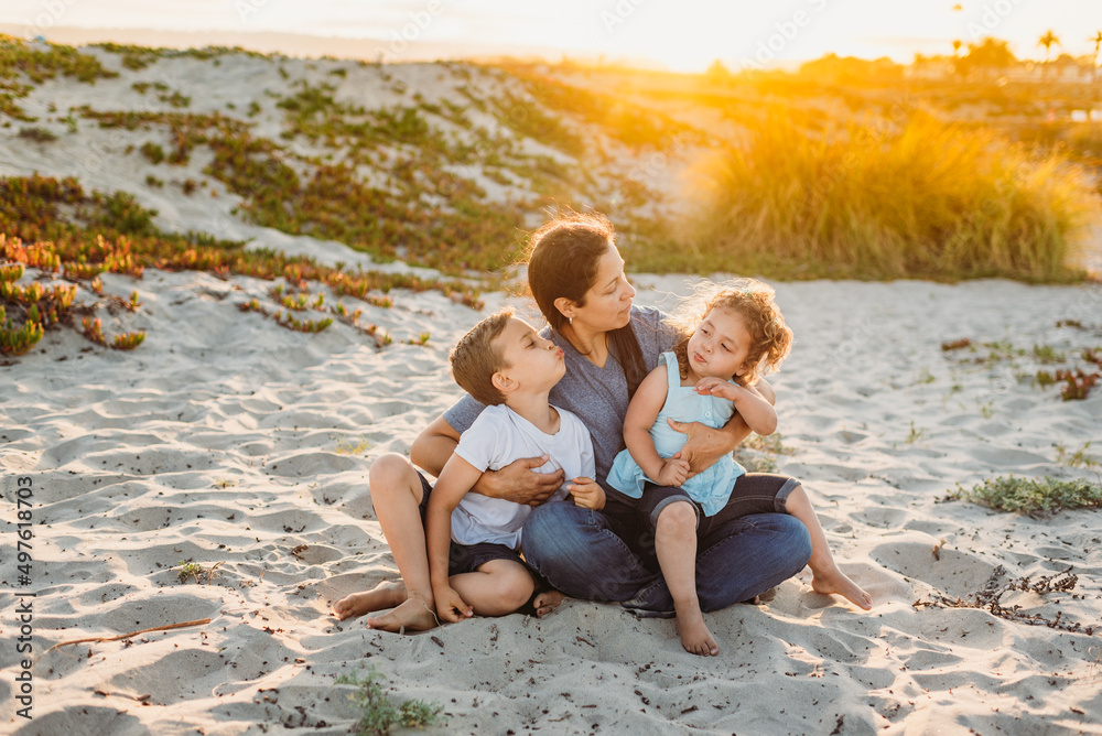 Smiling family sitting in sand at sunset Smiling family sitting in sand at sunset