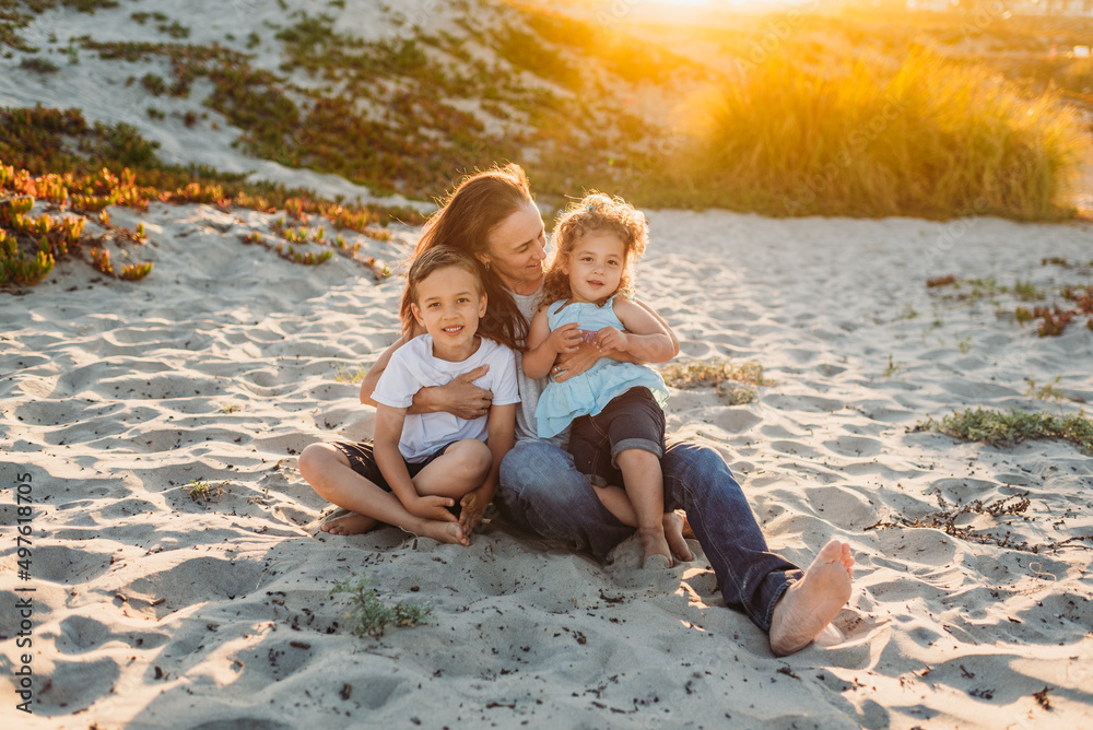 Happy kids sitting in sand with mom Happy kids sitting in sand with mom