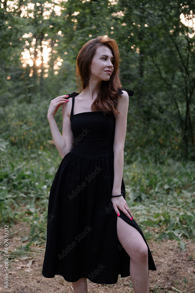 portrait of sensual young woman in a black dress in the forest. freedom, loneliness. nature loving