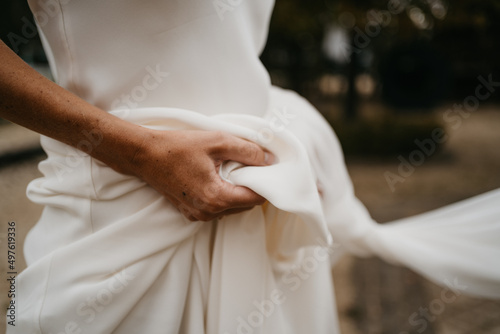 closeup bride holding white dress photo