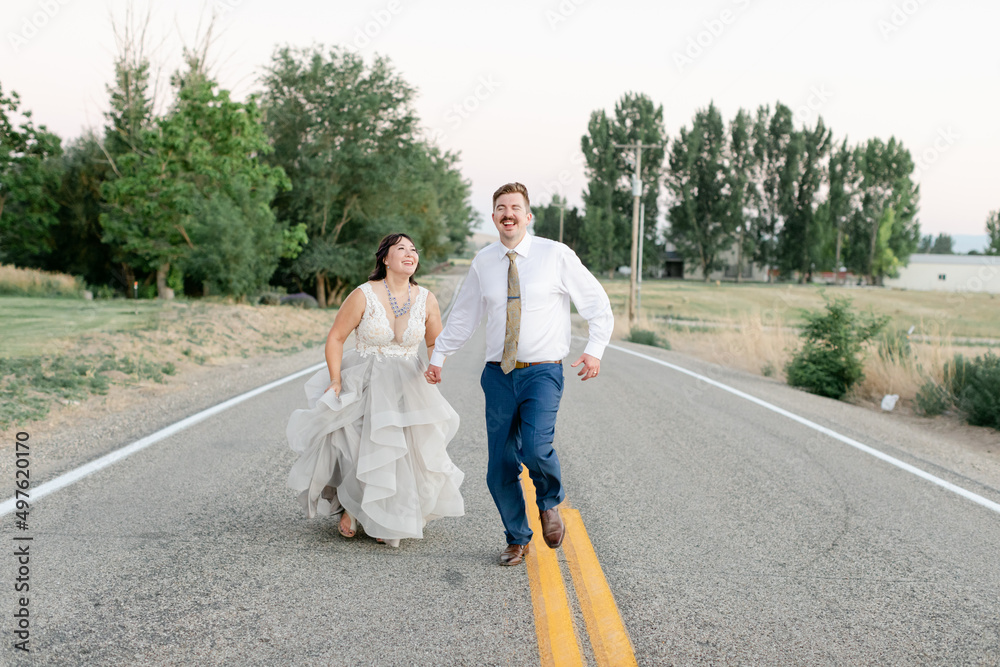 Newly Married Couple Running on Road in Wedding Attire Newly Married Couple Running on Road in Wedding Attire