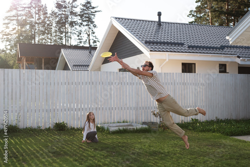 Father catching frisbee while playing with daughter photo