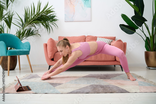 Full body of young flexible female in sportswear doing stretching at home photo