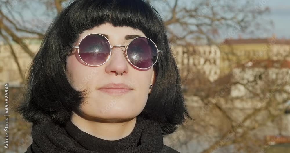 Portrait of a young woman with rocker extravagant make-up and black glasses setting her face to the sun. Portrait of a young woman with rocker extravagant make-up and black glasses setting her face to the sun.