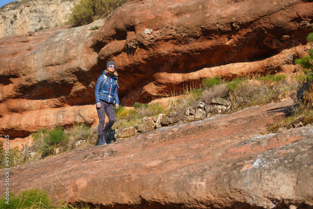 Young female explorer hiking on rocky cliff in sunlight Young female explorer hiking on rocky cliff in sunlight