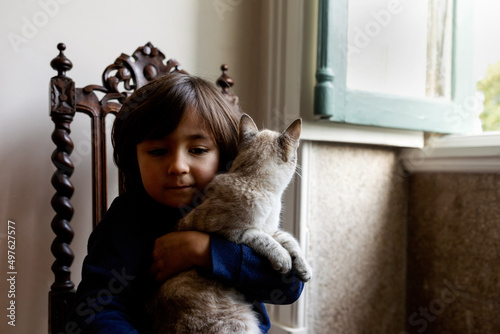 Little kid holding cat indoor photo