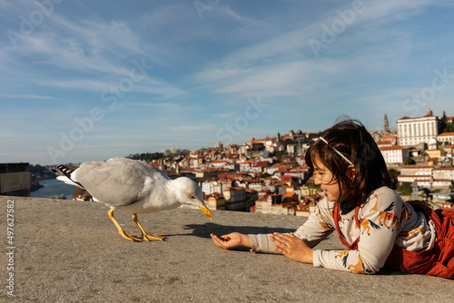 Cute girl feeding seagull in Portugal photo