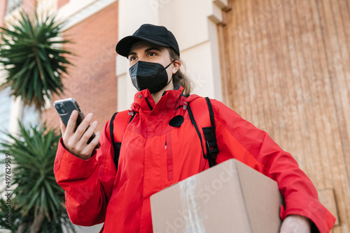 Delivery woman waiting for addressee with box on street