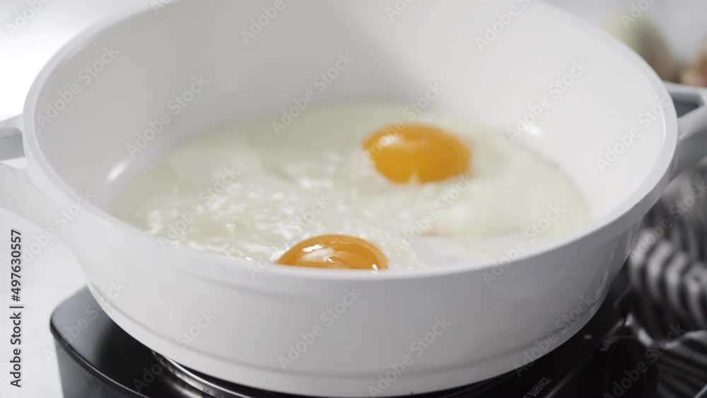 Close up view. Frying farm fresh eggs in a white skillet. Close up view. Frying farm fresh eggs in a white skillet.