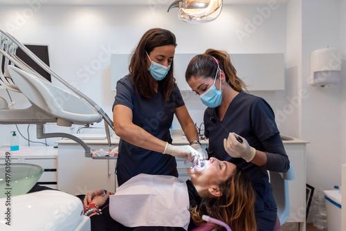 Female dentists treating patient with cheek retractor photo