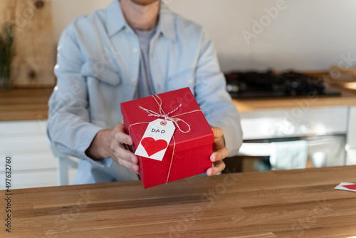 Man showing father's gift to camera in kitchen photo