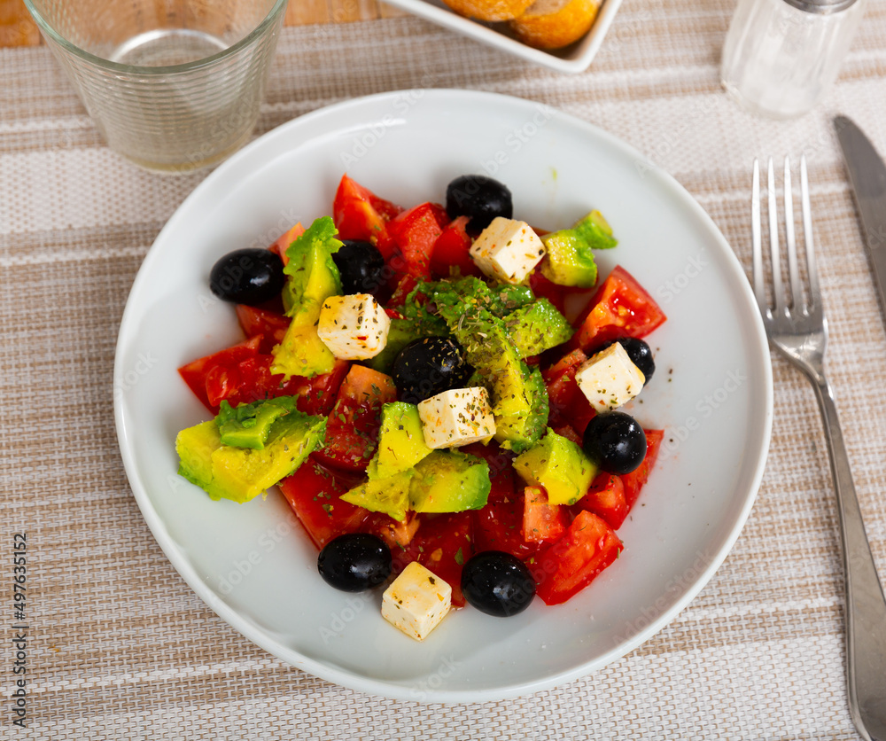 Light vegetable salad made from sweet peppers, tomatoes, avocado, olives, cheese and sprinkled with seasoning on top