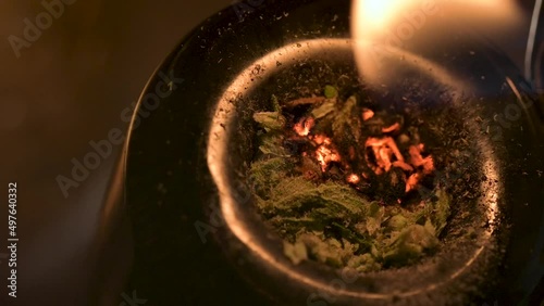 Macro view of lighting marijuana and smoking through a large water pipe.  Burning cannabis releasing THC and CBD.  Recreational drug use concept.