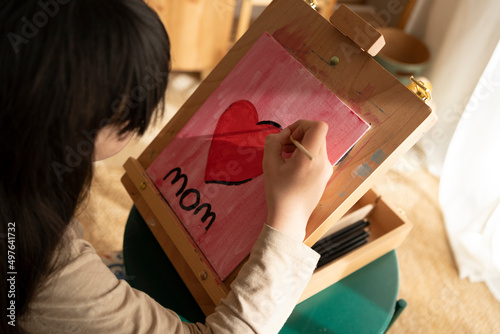 Girl painting a heart on tabletop easel photo