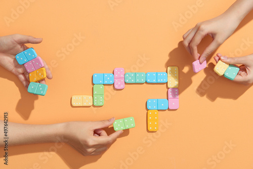 Two women playing domino on beige background