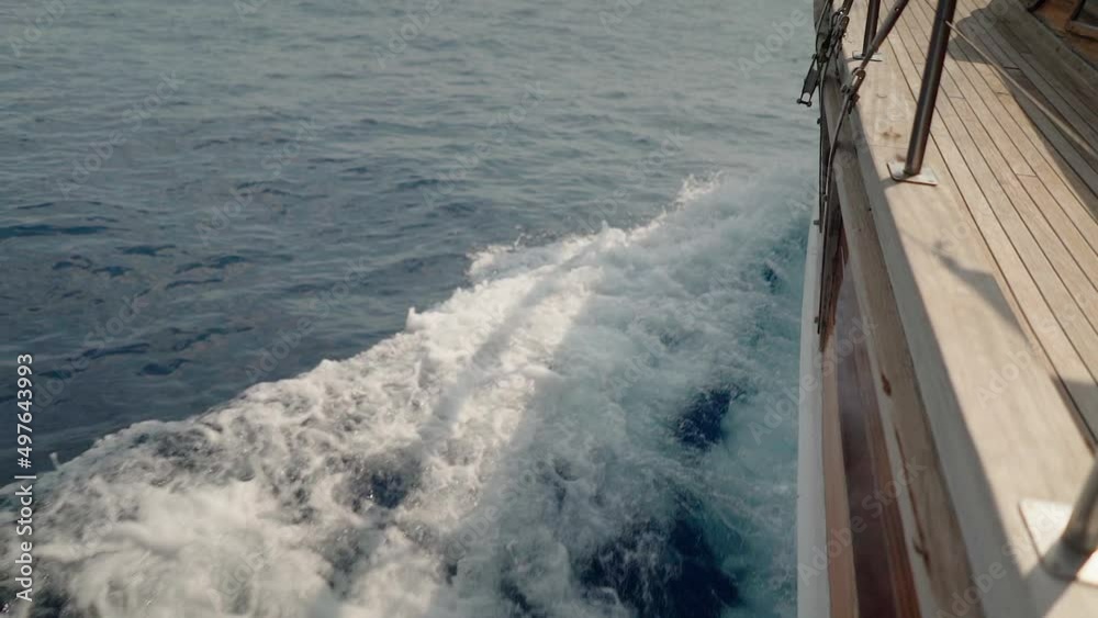 Slow Motion: Beautiful wooden sailboat produces bow wake in blue water
