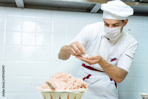 Wallpaper Mural Male chef cook prepares dumplings and wearing face protective medical mask for protection from virus disease at restaurant kitchen. Torontodigital.ca