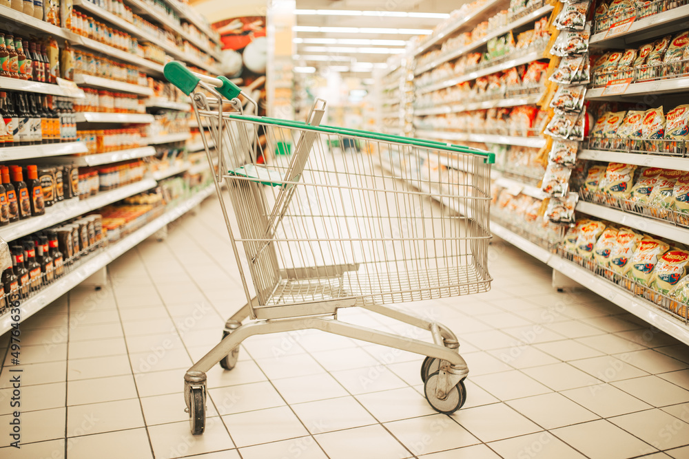 Supermarket interior, empty green shopping cart. Supermarket interior, empty green shopping cart.