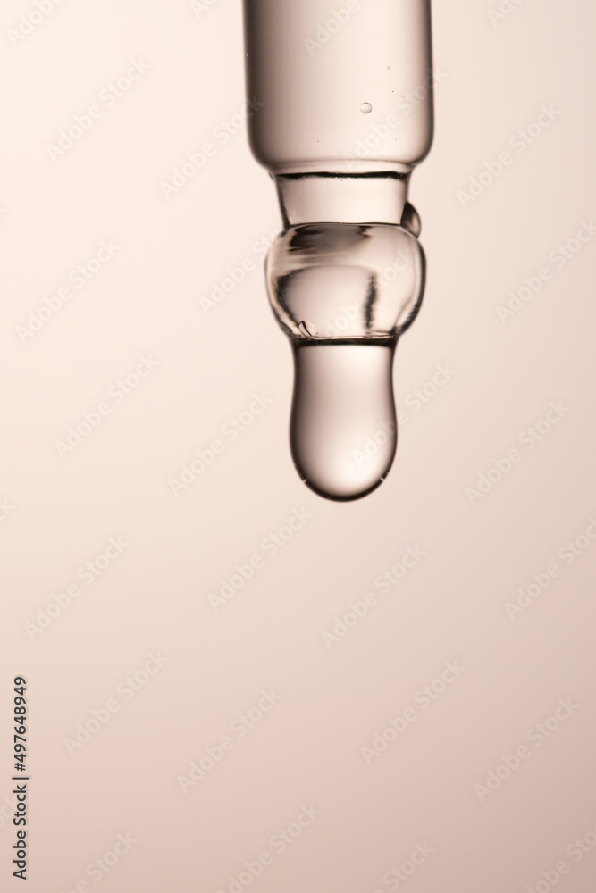 Pipette with serum, gel, oil or other cosmetic product on a beige background. Pipette with serum, gel, oil or other cosmetic product on a beige background.