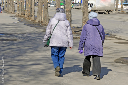Two women walk along the sidewalk on a spring day